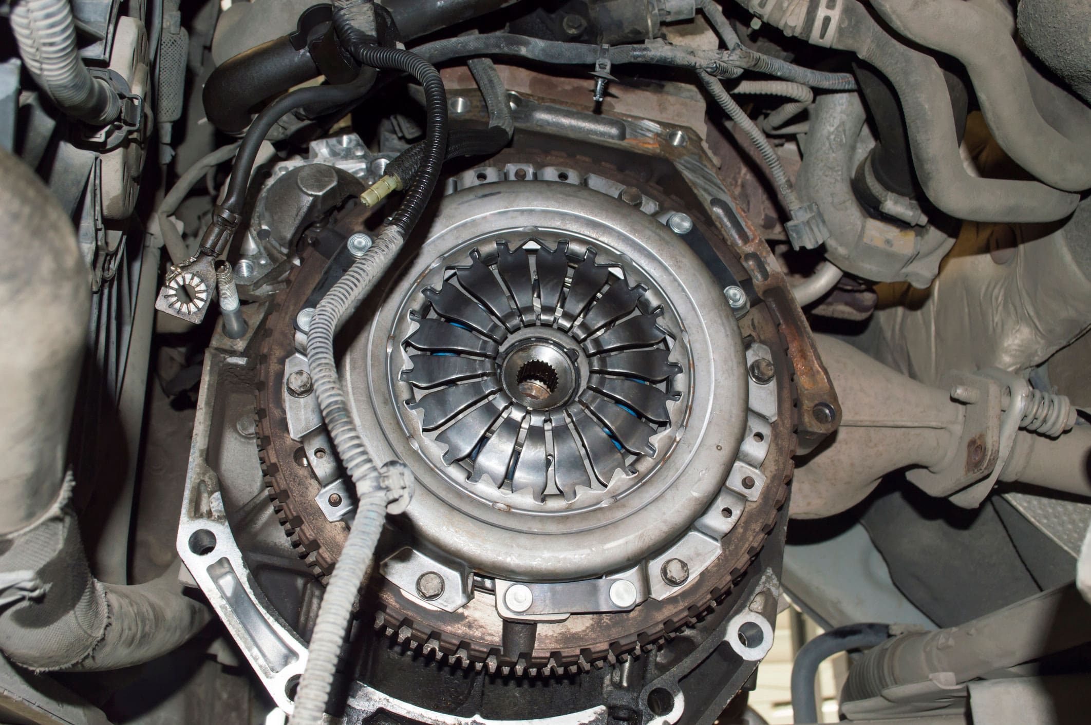 View of the engine compartment of the car from the side of the removed manual transmission. The clutch basket and the gear ring of the flywheel are visible